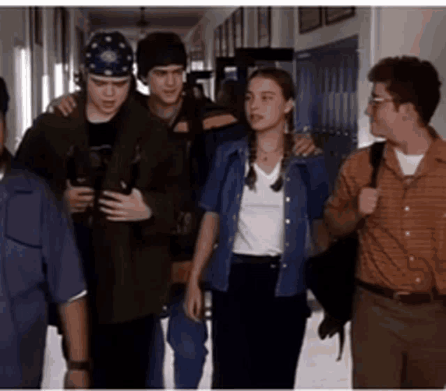 a group of people walking down a hallway with one wearing a bandana on his head