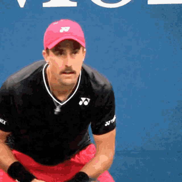 a man wearing a red hat and a black shirt with yonex written on the sleeves