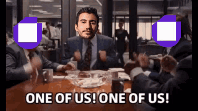 a man in a suit sitting at a table with the words one of us one of us below him