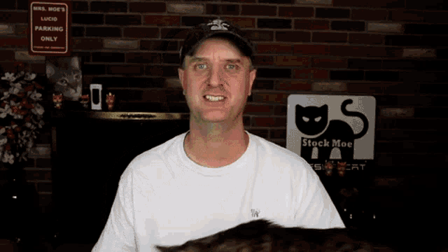 a man holds a cat in front of a stock moe sign
