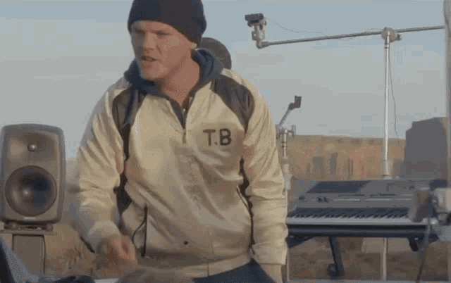 a man wearing a jacket with the letter tb on the front