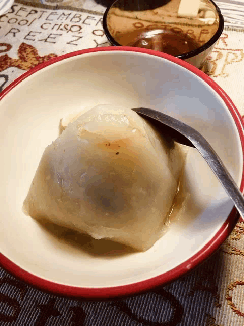 a white bowl with a red rim and a spoon on a table with a september cool crisp reez written on it