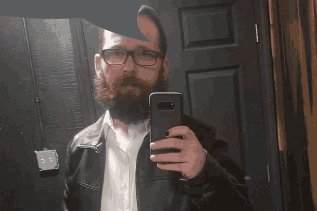 a man with a beard and glasses takes a selfie