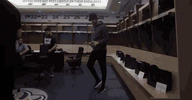 a man stands in a locker room with a sign that says defeat does not rest lightly on their shoulders