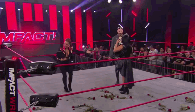 a couple standing in a wrestling ring with the word impact on the wall behind them