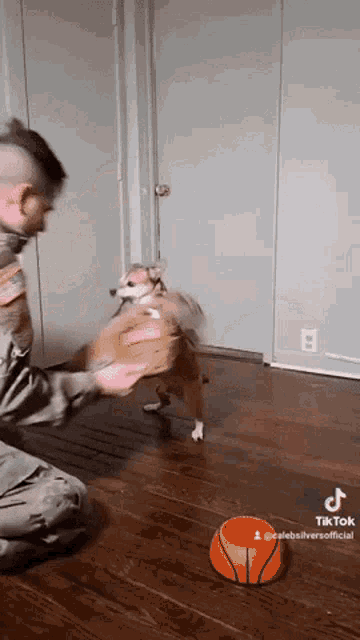 a man and a dog are playing with a basketball and a bowl of food on the floor .