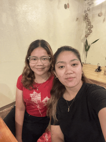 a woman wearing a red shirt with a maple leaf on it sits next to a woman wearing a black shirt