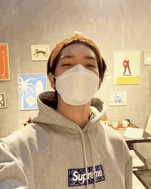 a man wearing a face mask and a supreme sweatshirt