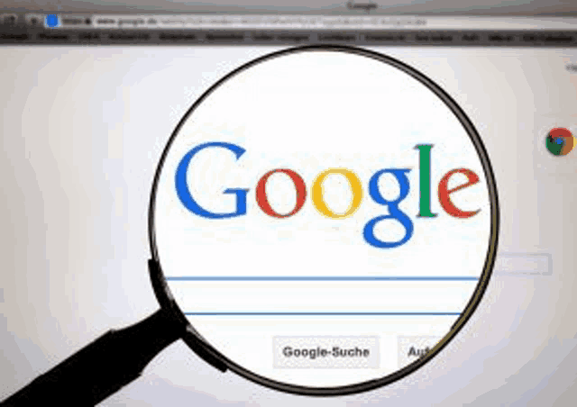 a magnifying glass is looking at the google search engine on a computer screen .