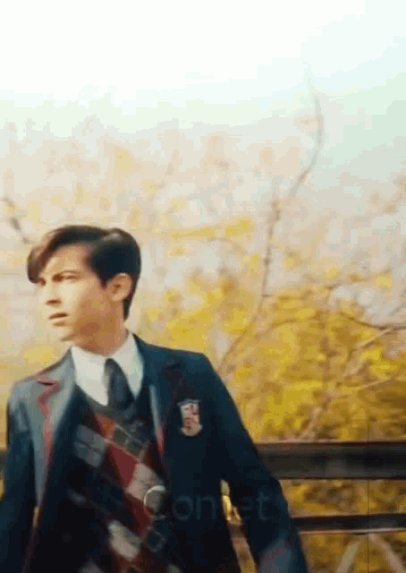 a young man in a suit and tie is walking down a bridge .