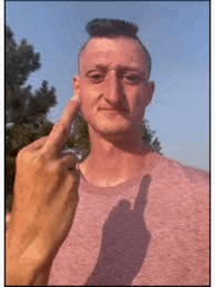 a man with a mohawk is giving the middle finger and his shadow is visible .