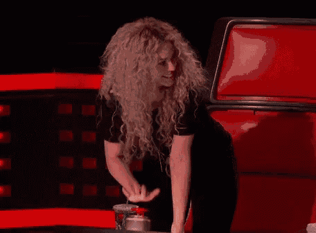 a woman with curly hair is sitting in a chair on a red couch .