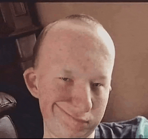 a man with a bald head is making a funny face while sitting on a couch .