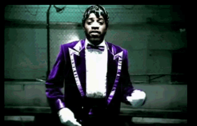 a man in a purple tuxedo and white gloves is dancing