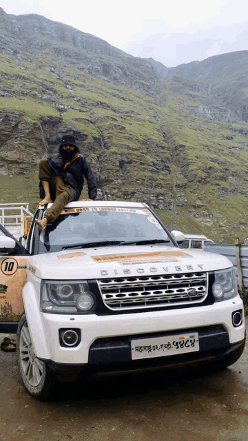 a man is sitting on the roof of a discovery car