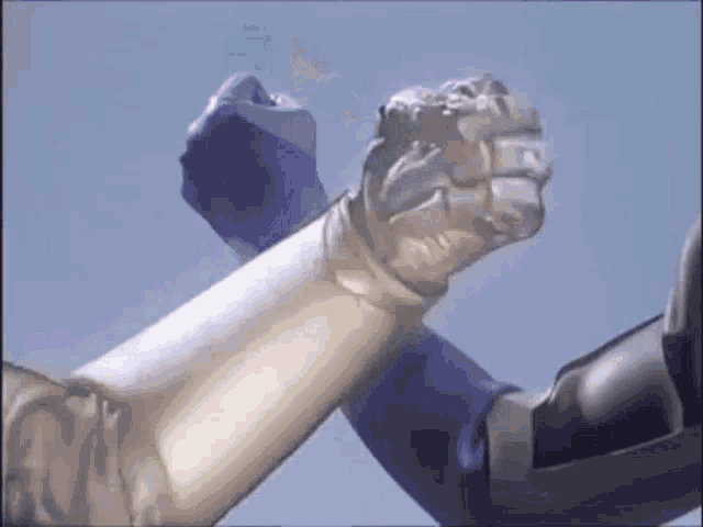 two robots are shaking hands in front of a blue sky