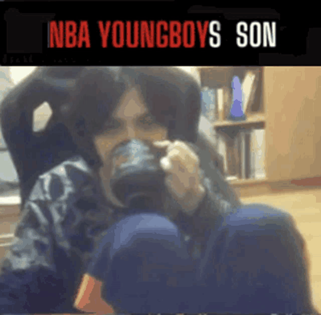 a man sitting in a chair drinking from a cup with the words nba youngboys son written above him