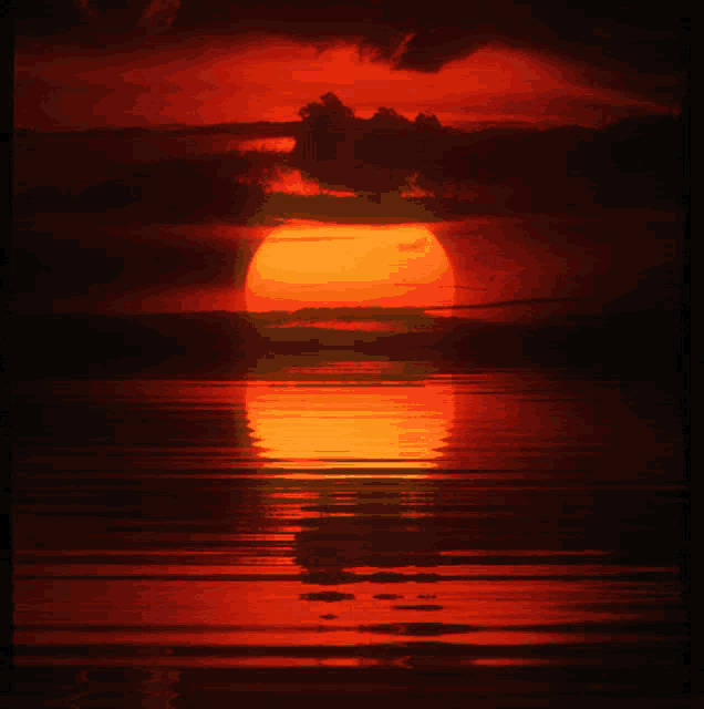 a red sunset over a body of water with a reflection of the sun