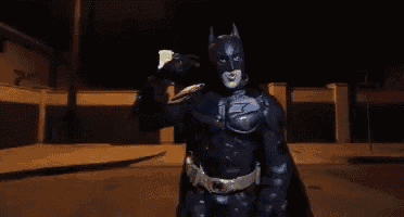 a man in a batman costume is holding a cup