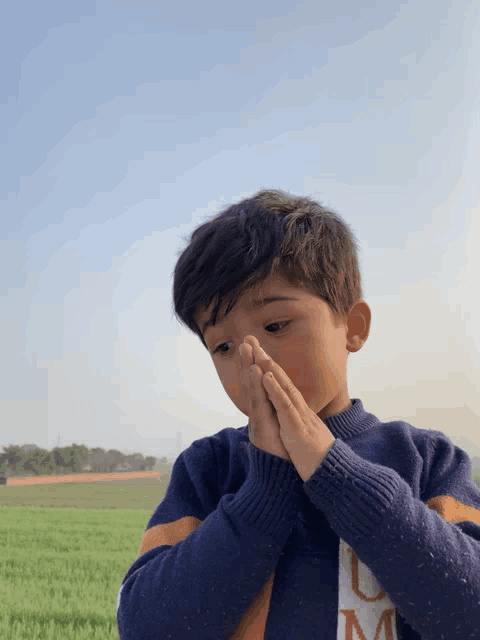 a young boy wearing a blue sweater with the letter m on the front