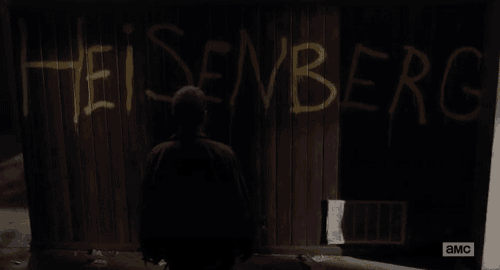 a man is standing in front of a wooden wall with the word heisenberg written on it .