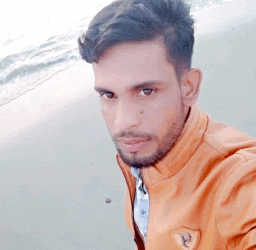 a man with a beard is taking a selfie at the beach .