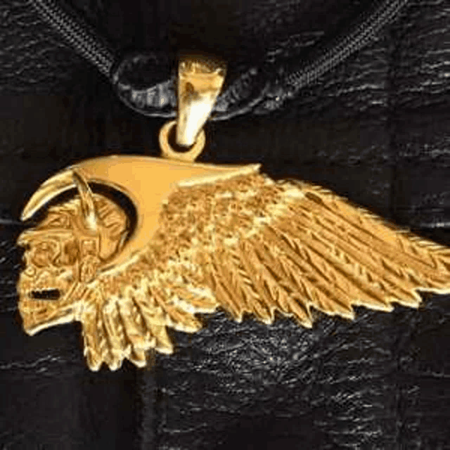 a close up of a gold wing pendant on a black necklace .