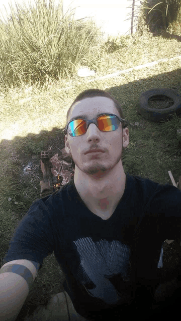 a young man wearing sunglasses and a black shirt takes a selfie