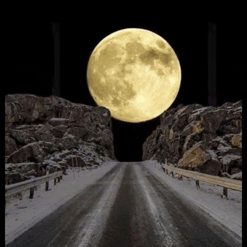 a full moon shines over a snowy mountain road