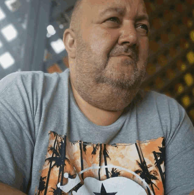 a man with a beard is wearing a shirt with palm trees and a star on it