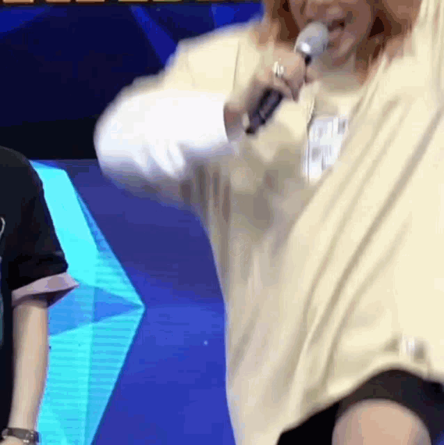 a woman is singing into a microphone while standing in front of a blue screen .