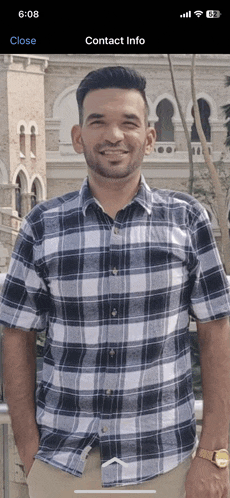 a man in a plaid shirt stands in front of a building with contact info displayed