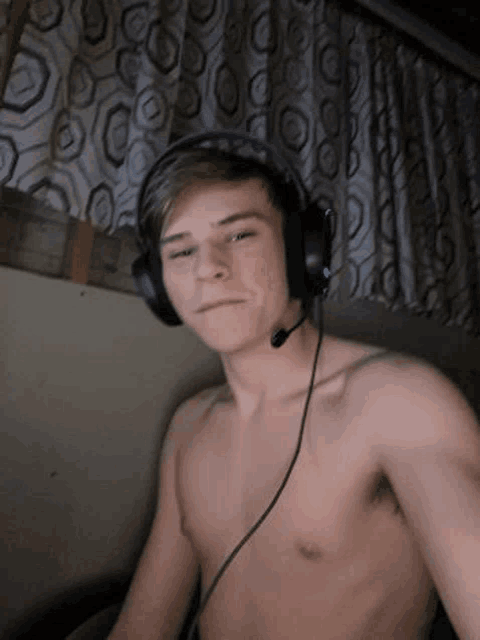 a shirtless young man is wearing headphones and a microphone .