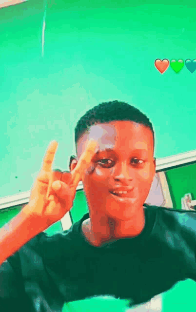 a young man giving a peace sign with hearts on the wall behind him