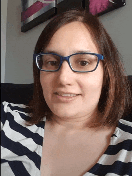 a woman wearing glasses and a striped shirt smiles at the camera