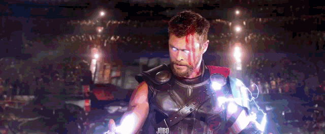 thor is holding a lightning bolt in his hand in front of a crowd in a stadium .