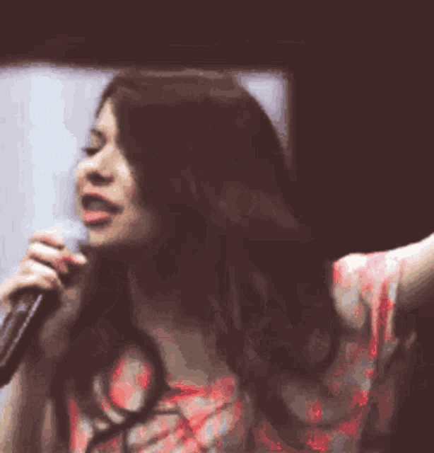 a woman is singing into a microphone with her hand outstretched