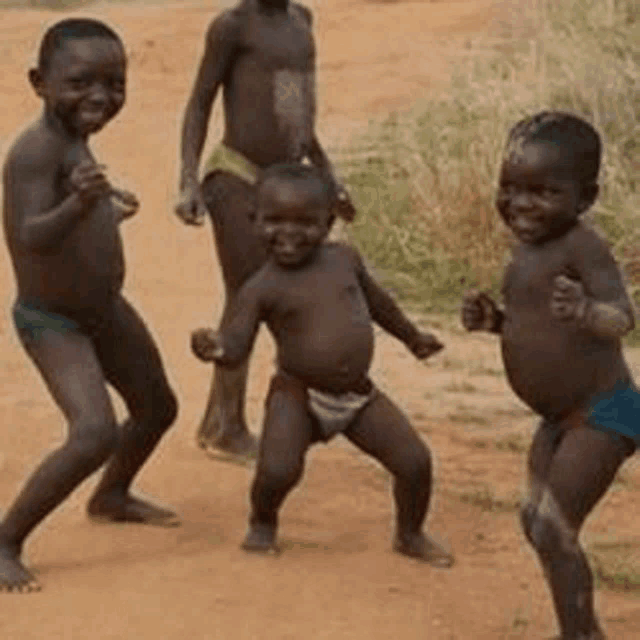 a group of young boys are dancing in the dirt .