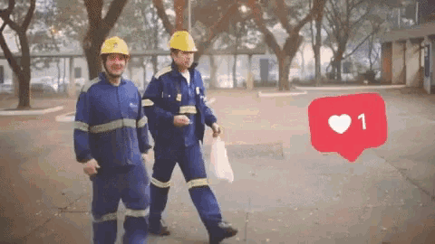 two men wearing hard hats are walking down a street with a red heart with the number one on it