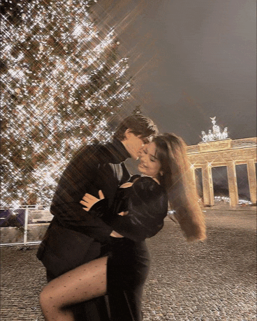 a man and a woman kissing in front of a christmas tree