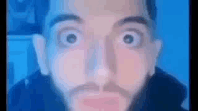 a man with a beard is making a funny face in front of a blue screen .