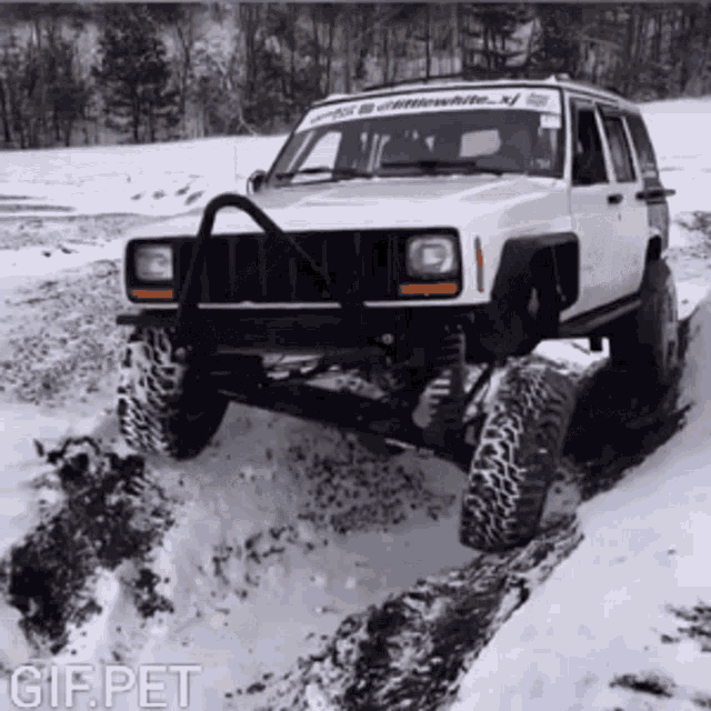 a white jeep is driving through a snowy field with a gif pet watermark