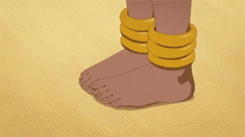 a close up of a person 's feet wearing gold bracelets .