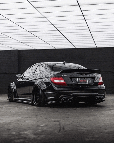 a black mercedes c63 is parked in a garage with a license plate that says california