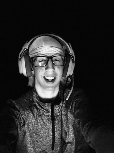 a man wearing headphones and glasses takes a selfie in the dark