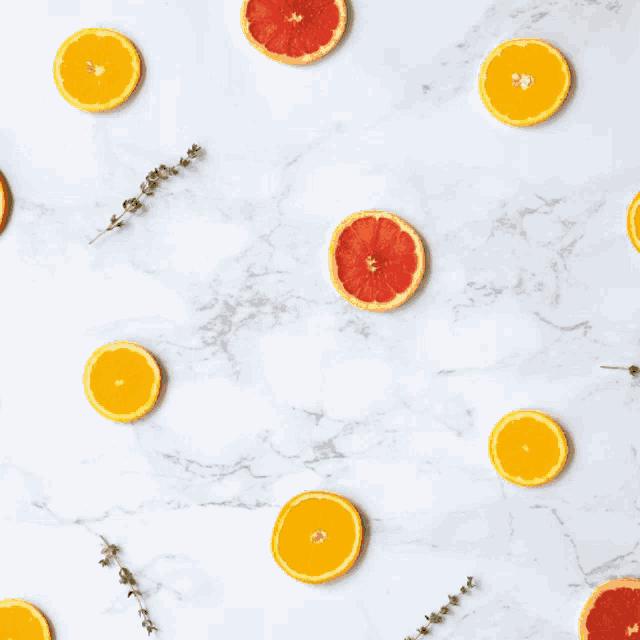 orange slices and grapefruit slices on a white marble surface