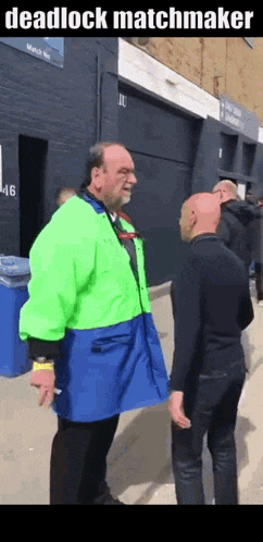a man in a green jacket is talking to another man .