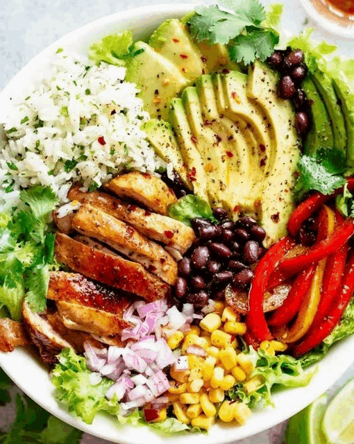 a white bowl filled with a variety of food including rice avocado beans and peppers