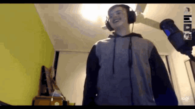 a man wearing headphones is standing in front of a logitech logo