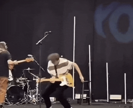 a man is playing a guitar on stage in front of a microphone